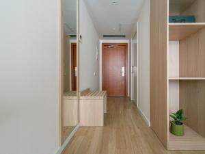 a hallway with wooden floors and a door with a plant at limehome Barcelona Carrer de Besalú 82 in Barcelona