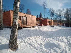 una baita di tronchi nella neve accanto a un albero di Fox House Tisá / Rájec a Tisá