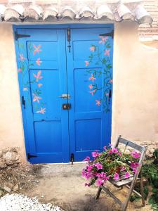 a blue door with a bench and flowers in front of it at Albergue Villares de Orbigo, Albergue de Peregrinos in Villares de Órbigo