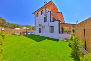 une maison avec une cour avec de l'herbe verte dans l'établissement Villa Grando 2, à Kaş