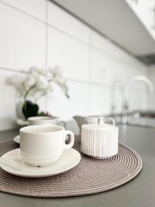 two white cups and saucers on a kitchen counter at Apartment Doris in Tomislavgrad
