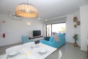 a living room with a table and a blue couch at Sao Rafael Beach Apartment - By Dalma Portuguesa in Albufeira