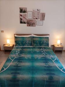 una camera da letto con un letto con un piumone blu e due lampade di Gentarrubia - a casa nel cuore della città a Oristano