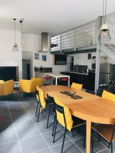 a dining room with a wooden table and yellow chairs at Maison Jeanne d’Arc in Mennetou-sur-Cher