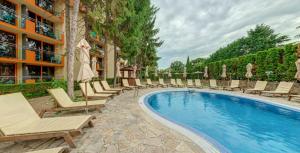 a pool with chairs and umbrellas next to a building at Hotel Sunrise Golden Sands in Golden Sands