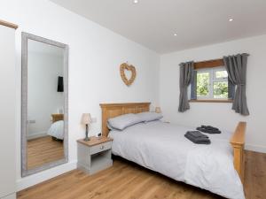 um quarto com uma cama e um espelho grande em Pass the Keys Adorable 1 bedroom Country Cottage couplessingles em Bodewryd