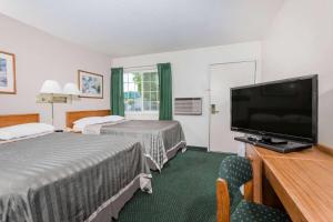 a hotel room with two beds and a flat screen tv at Travelodge by Wyndham Grants Pass in Grants Pass