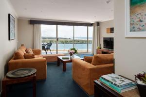 a living room with brown furniture and a large window at Rydges Hotel Port Macquarie in Port Macquarie