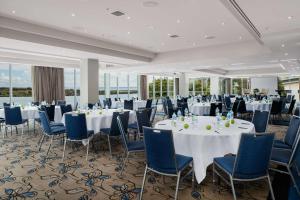 uma sala de banquetes com mesas brancas e cadeiras azuis em Rydges Hotel Port Macquarie em Port Macquarie