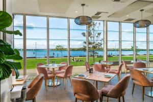 a restaurant with tables and chairs and large windows at Rydges Hotel Port Macquarie in Port Macquarie