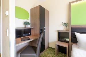a room with a bed, chair, desk and a tv at Novum Hotel Aldea Berlin Centrum in Berlin