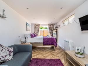 a bedroom with a bed and a couch at Pass the Keys Charming Chalet A Stones Throw From The Beach in Chichester