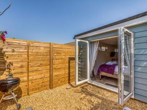 a small house with sliding glass doors and a bedroom at Pass the Keys Charming Chalet A Stones Throw From The Beach in Chichester