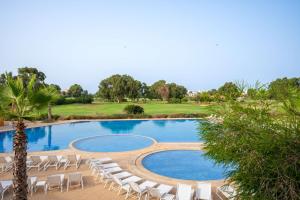 a swimming pool with chairs and a golf course at Radisson Blu Resort, Saidia Garden in Saïdia