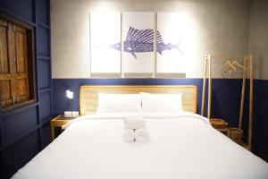 a bedroom with a large white bed with two towels on it at Tali-Yailai Hostel in Pattaya