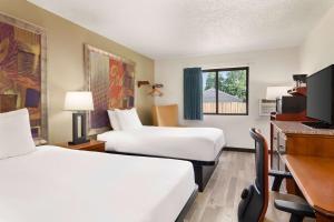 a hotel room with two beds and a desk at Baymont by Wyndham Hutchinson in Hutchinson