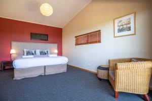 ein Schlafzimmer mit einem Bett und einem Stuhl in der Unterkunft Redgate Beach Escape in Witchcliffe