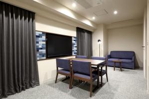 - une salle de conférence avec une table, des chaises et une télévision dans l'établissement Dormy Inn Okayama Natural Hot Spring, à Okayama