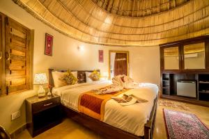 a bedroom with a large bed with a wooden ceiling at Bhavya Resort - Luxury Boutique Desert Camp in Jaisalmer