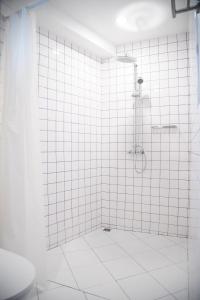 a bathroom with a shower with white tiled walls at Tali-Yailai Hostel in Pattaya