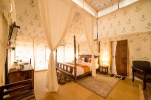 1 dormitorio con cama con dosel en una habitación en Bhavya Resort - Luxury Boutique Desert Camp en Jaisalmer