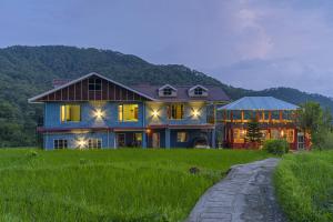 a large house on a grassy field with a pathway at Zostel Homes Harabhag, Jogindernagar in Bīr