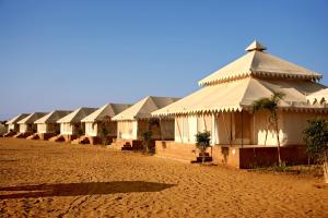 a row of white buildings on a dirt field at Bhavya Resort - Luxury Boutique Desert Camp in Jaisalmer