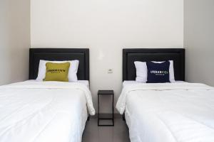 2 letti posti uno accanto all'altro in una stanza di Urbanview Hotel Syariah John Sweet Home by RedDoorz a Tegal