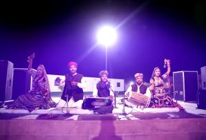 a group of people sitting on a stage with a light at Bhavya Resort - Luxury Boutique Desert Camp in Jaisalmer