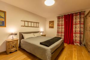 1 dormitorio con cama y cortina roja en Maison La Louche - Courmayeur, en Courmayeur