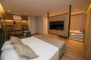 a bedroom with a large white bed and a flat screen tv at Origens Hotel in São Luís Gonzaga