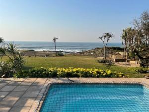 a swimming pool with a view of the ocean at The Beach House in Port Shepstone