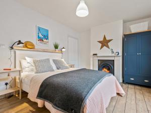 a bedroom with a bed with a blue cabinet and a fireplace at Limewood Newly Renovated High End Home by the Sea in Whitstable