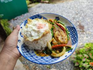 a person holding a blue and white plate of food at Baan Suan Tondin 