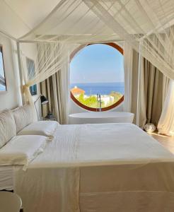 1 dormitorio con 1 cama grande y ventana grande en Agapanto Luxury Accommodation, en Isquia