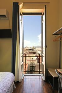 a bedroom with a door open to a balcony at Hotel Roma 62 in Palermo