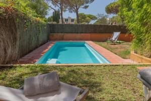 a swimming pool in the yard with a chair in the grass at Illes Medes a el Golfet in Palafrugell