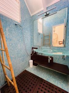 a blue tiled bathroom with a sink and a mirror at Blue Lagoon, cottage les pieds dans l eau in Terre-de-Haut