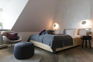 a bedroom with a bed and a chair at Hotel Aarnhoog in Keitum