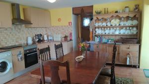 a kitchen with a wooden table with chairs and a washing machine at Casa da Casimira in Miranda do Corvo