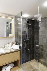 ein Bad mit einer Dusche, einem Waschbecken und einem Spiegel in der Unterkunft Hotel Aarnhoog in Keitum