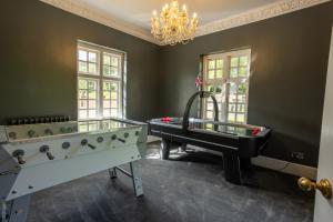 Habitación con 2 mesas de ping pong y lámpara de araña. en Eastwood Observatory: 12 bedrooms, swimming pool and tennis court en Hailsham