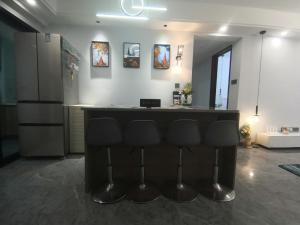 a kitchen with a bar with four stools at kayla泉州晋江吾悅广场五店市万达轻奢风投影3房 in Jinjiang