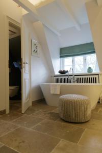 a bathroom with a large tub and a sink at Hotel Aarnhoog in Keitum