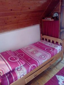 a small bed with a pink blanket on it at Apartmani Planinska kuća, Jagodnja in Krupanj