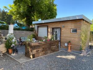 a small wooden cabin with a stone wall at Die Pilgerbox, Tiny House trifft Urlaub, optional mit Sauna und Whirlpool in Dahlem
