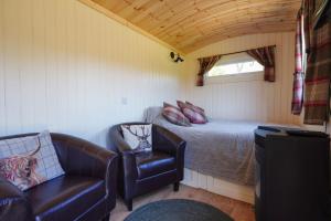 um pequeno quarto com uma cama e uma cadeira em The Laburnum Retreat Shepherd Hut private hot Tub em Upper Hulme