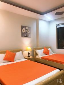 twee bedden in een kamer met oranje lakens bij Bao Tran Homestay in Da Nang