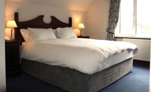 een slaapkamer met een groot bed met witte lakens en kussens bij Falls of Lora Hotel in Oban