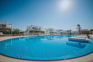 a large blue swimming pool with buildings in the background at Двухкомнатные апартаменты в жилом комплексе Caesar Beach D1 Flat15 in Boğaz +27 photos